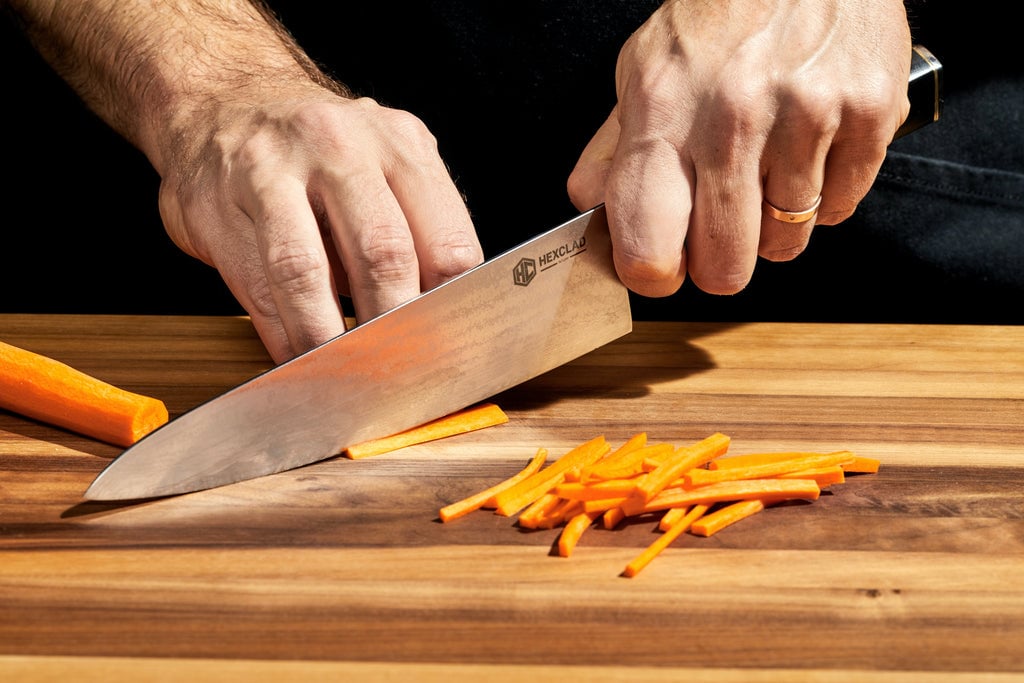 hands using knife to cut carrots